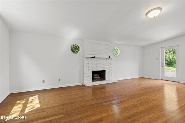 unfurnished living room featuring lofted ceiling, hardwood / wood-style floors, and a fireplace