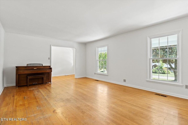 empty room with plenty of natural light, ornamental molding, and light wood-type flooring