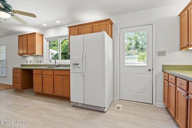 kitchen featuring white refrigerator with ice dispenser, ceiling fan, and sink