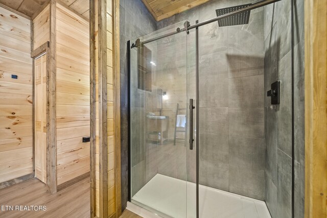 bathroom with hardwood / wood-style flooring, walk in shower, and wooden walls