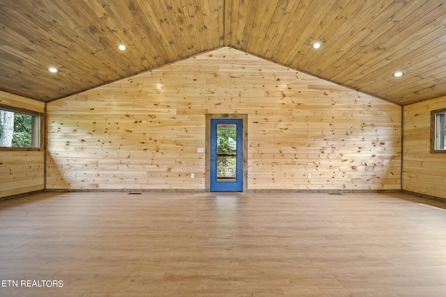 empty room featuring lofted ceiling, light wood-type flooring, wooden walls, and wood ceiling