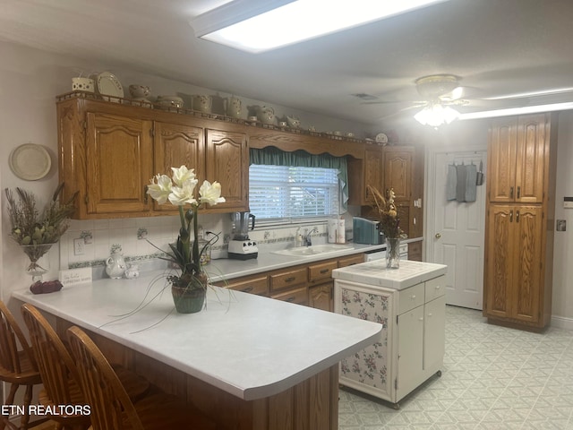 kitchen featuring sink, kitchen peninsula, backsplash, and ceiling fan