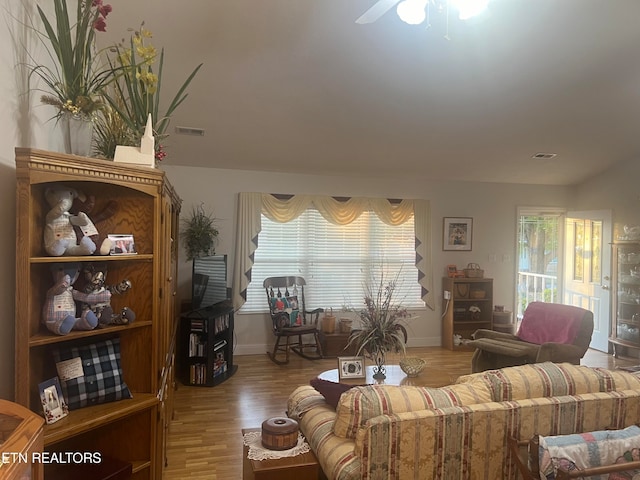 living room with a wealth of natural light, light hardwood / wood-style flooring, and ceiling fan