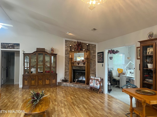 living room with lofted ceiling with skylight, hardwood / wood-style floors, and a fireplace