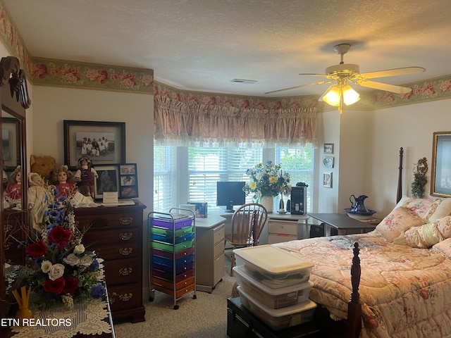 bedroom featuring a textured ceiling, light colored carpet, and ceiling fan