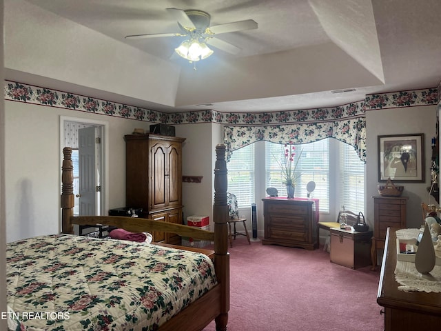 bedroom featuring light carpet, lofted ceiling, a tray ceiling, and ceiling fan