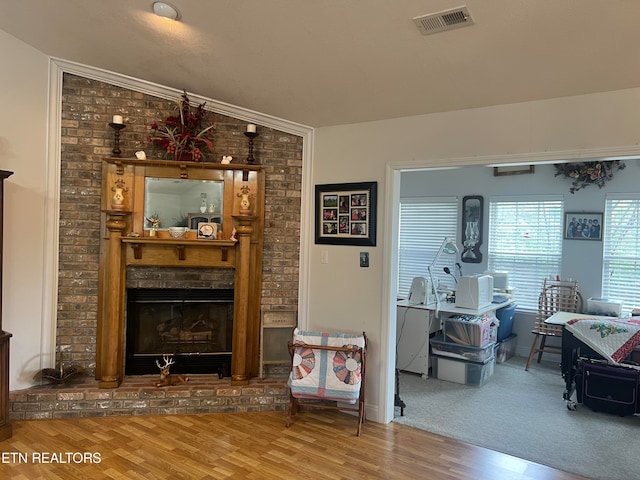 living room with vaulted ceiling, a brick fireplace, and wood-type flooring