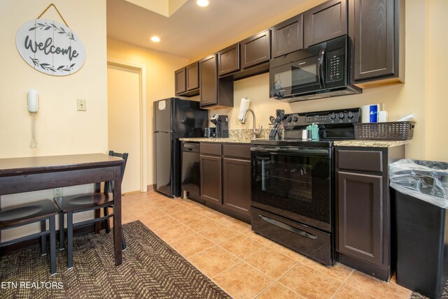 kitchen with black appliances, light tile patterned floors, and dark brown cabinets