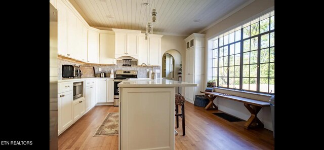 kitchen with stainless steel appliances, white cabinetry, light hardwood / wood-style floors, and a center island