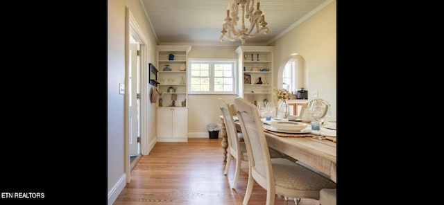 dining space featuring light wood-type flooring, crown molding, and a chandelier