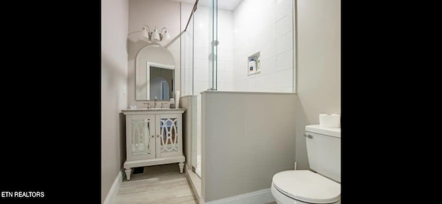 bathroom featuring walk in shower, vanity, toilet, and hardwood / wood-style flooring