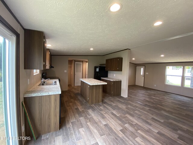 kitchen featuring black fridge, sink, a kitchen island, a textured ceiling, and dark wood-type flooring