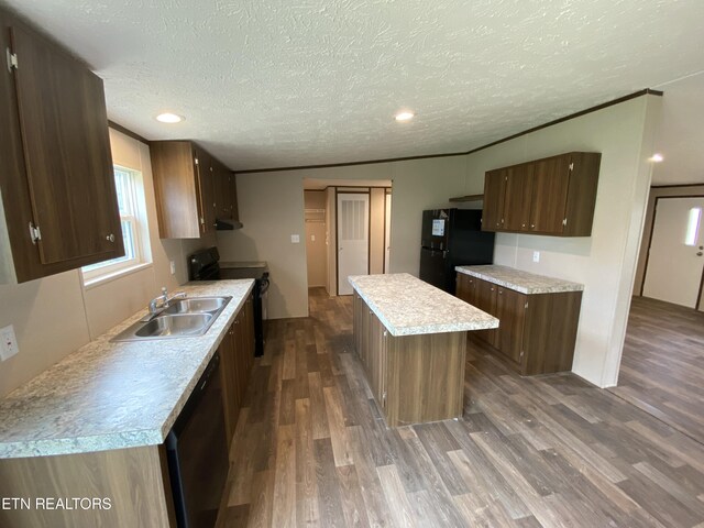 kitchen with dark wood-type flooring, a textured ceiling, black appliances, a center island, and sink