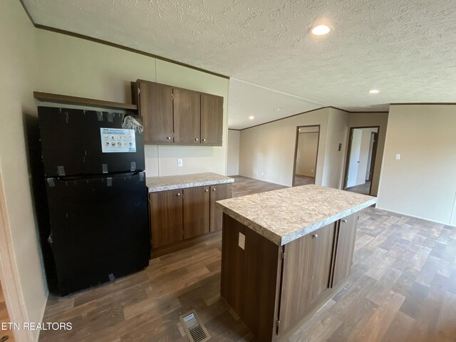 kitchen featuring wood-type flooring, a textured ceiling, and black fridge