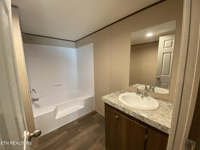 bathroom featuring shower / bath combination, a textured ceiling, hardwood / wood-style flooring, and vanity