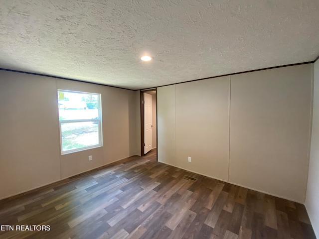 unfurnished room featuring a textured ceiling and dark hardwood / wood-style floors