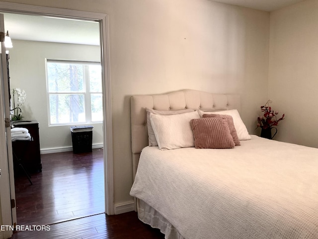 bedroom featuring baseboards and dark wood-type flooring