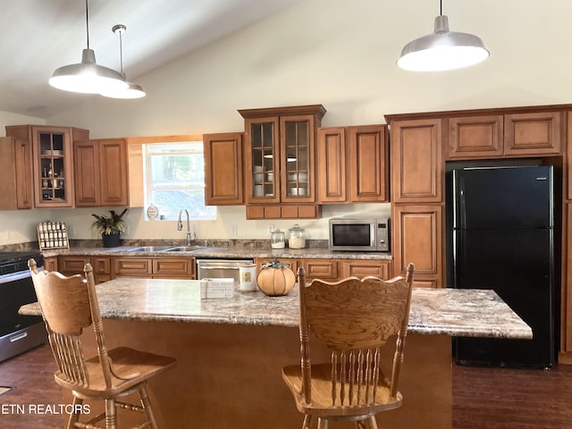 kitchen featuring glass insert cabinets, stainless steel appliances, a sink, brown cabinets, and decorative light fixtures