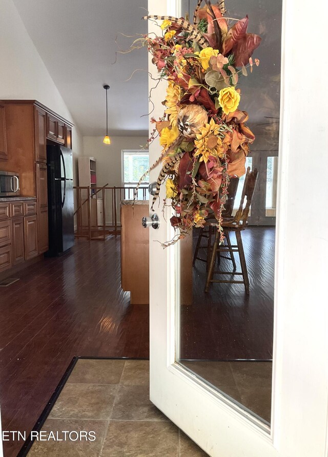 details featuring stainless steel microwave, brown cabinets, dark wood-style flooring, freestanding refrigerator, and a peninsula