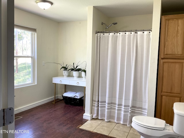 full bath with baseboards, wood finished floors, toilet, and a healthy amount of sunlight