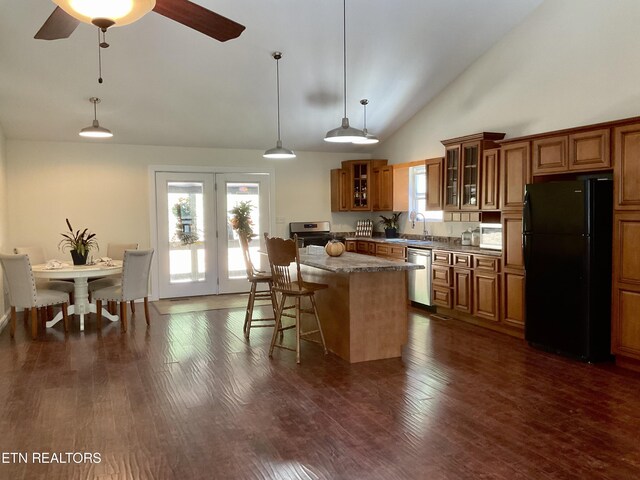 kitchen featuring brown cabinetry, glass insert cabinets, a breakfast bar, a center island, and stainless steel appliances