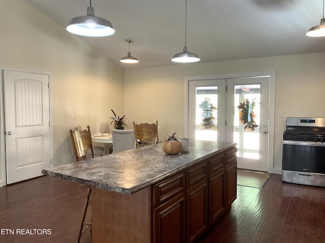 kitchen featuring dark countertops, a center island, stainless steel range with electric cooktop, and decorative light fixtures