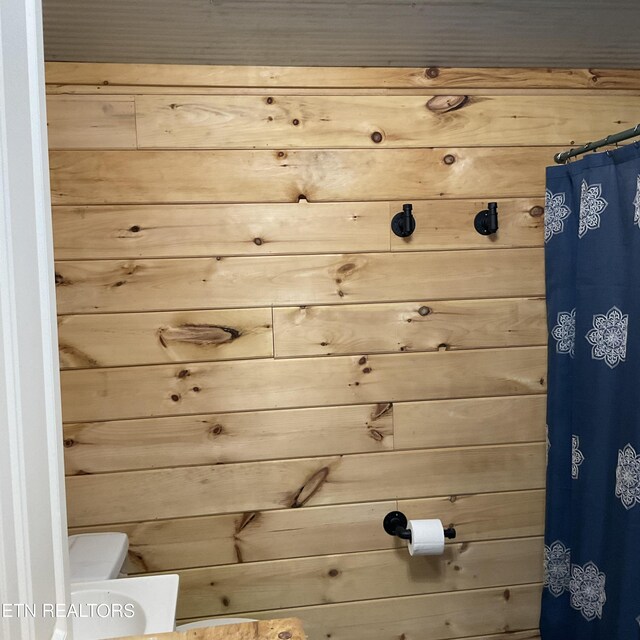 bathroom featuring toilet and wood walls