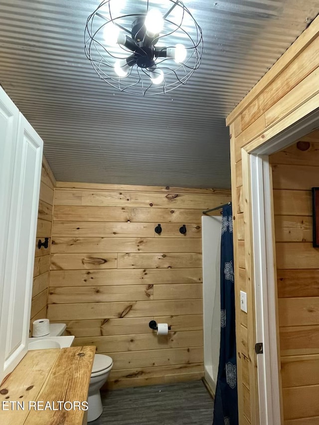 bathroom featuring a chandelier, wood walls, and toilet