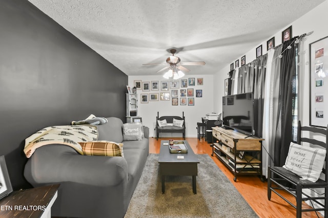 living room featuring a textured ceiling, hardwood / wood-style floors, and ceiling fan