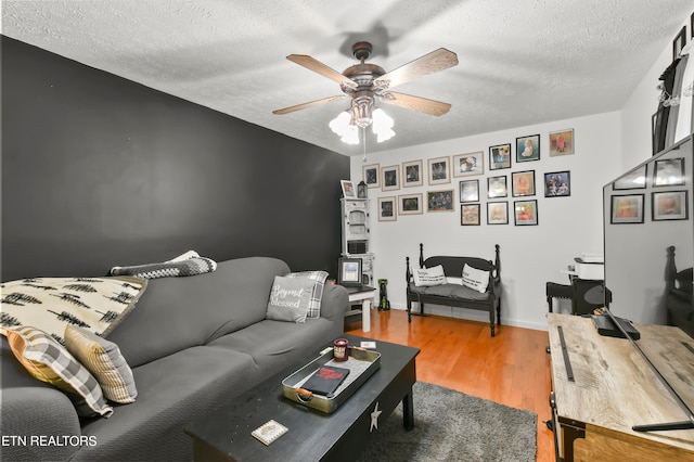 living room with ceiling fan, hardwood / wood-style flooring, and a textured ceiling