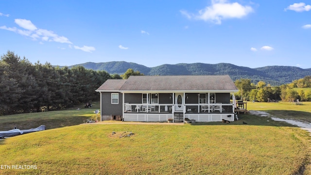 view of front facade with covered porch, a mountain view, and a front yard