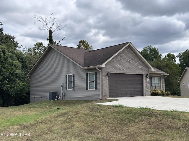 view of side of property with driveway, an attached garage, a yard, a shingled roof, and brick siding