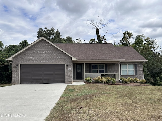 ranch-style house with driveway, covered porch, an attached garage, a front yard, and brick siding