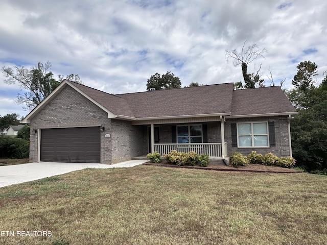 single story home with concrete driveway, brick siding, covered porch, and a front lawn