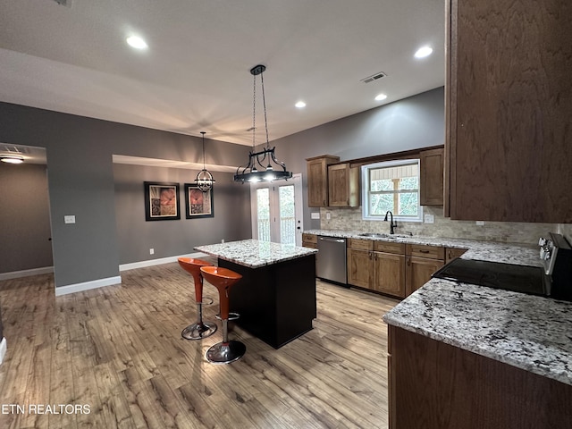 kitchen featuring visible vents, a kitchen island, a sink, dishwasher, and range