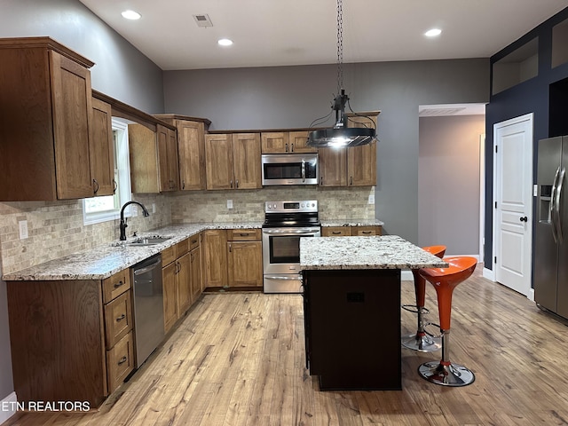 kitchen featuring visible vents, a center island, a breakfast bar, appliances with stainless steel finishes, and a sink