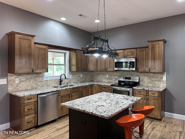 kitchen with a sink, a center island, light wood-type flooring, and stainless steel appliances