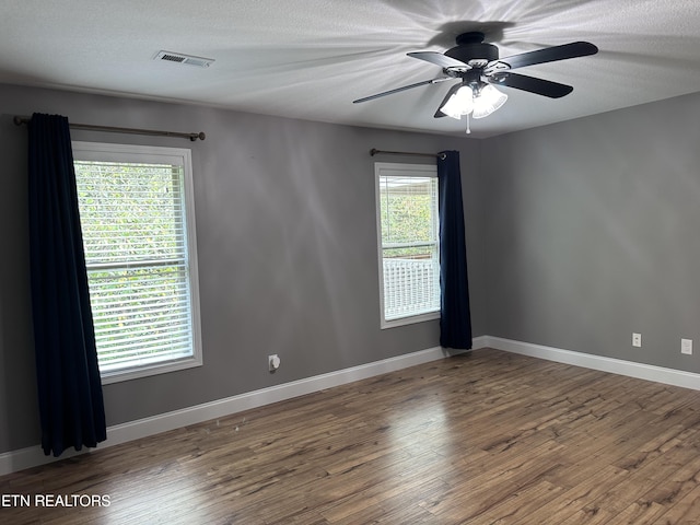 empty room featuring visible vents, wood finished floors, baseboards, and a textured ceiling