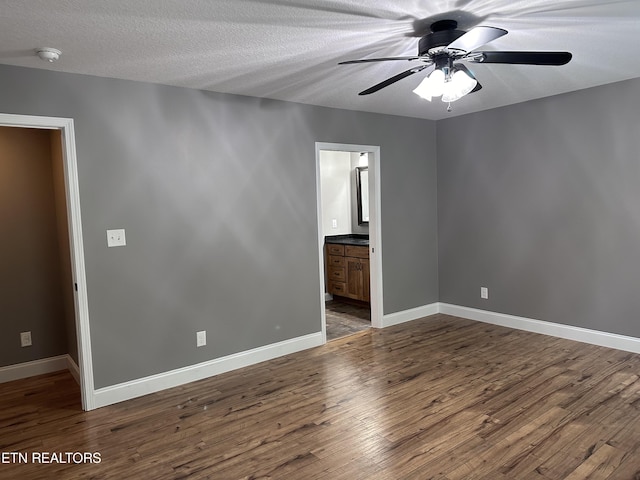 interior space featuring connected bathroom, baseboards, wood finished floors, a textured ceiling, and a ceiling fan