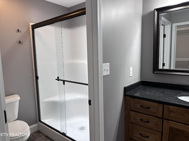 bathroom with vanity, baseboards, a shower stall, tile patterned floors, and toilet