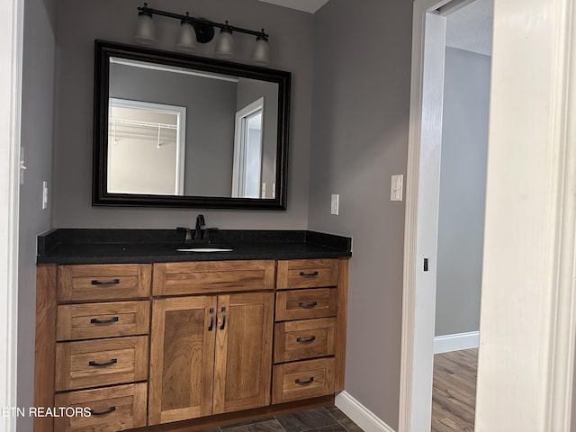 bathroom with baseboards, wood finished floors, and vanity