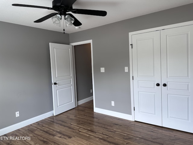 unfurnished bedroom featuring dark wood-style floors, baseboards, a closet, and ceiling fan