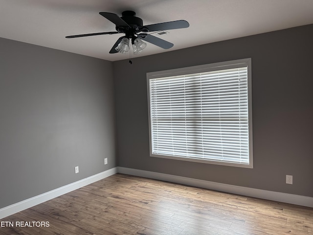 spare room with wood finished floors, baseboards, and ceiling fan