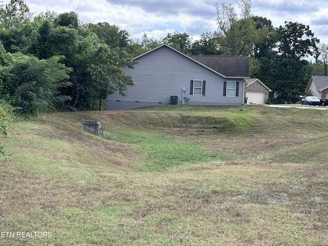 view of side of property with crawl space, a yard, a garage, and cooling unit