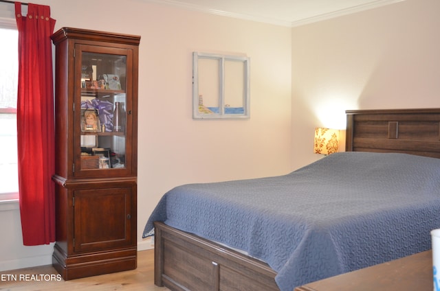 bedroom featuring multiple windows, light hardwood / wood-style floors, and ornamental molding