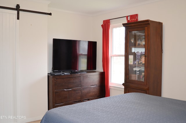 bedroom featuring crown molding and a barn door