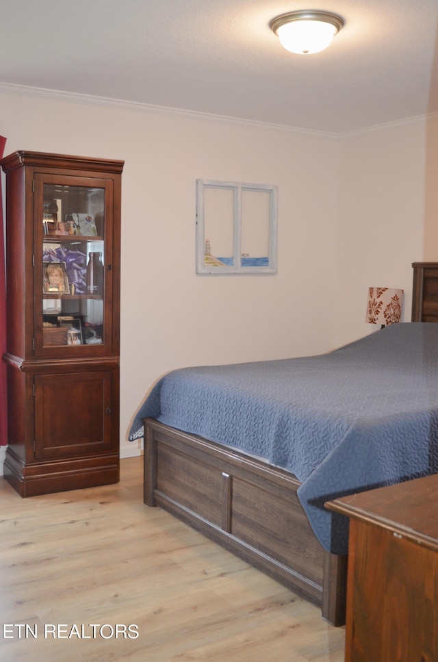 bedroom with crown molding and light hardwood / wood-style floors