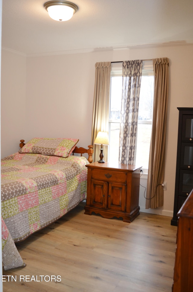 bedroom featuring light wood-type flooring and ornamental molding