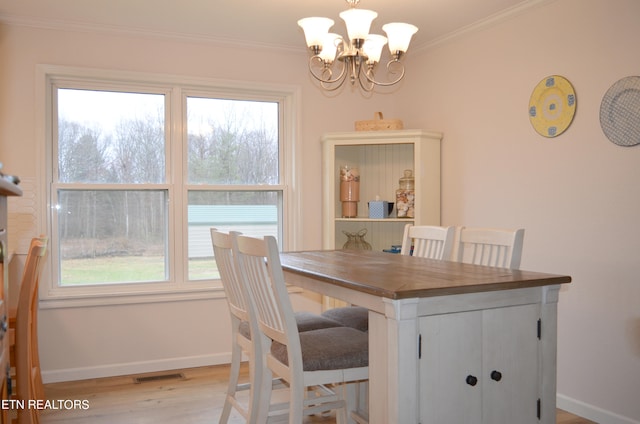 dining room featuring crown molding, a chandelier, and light hardwood / wood-style floors