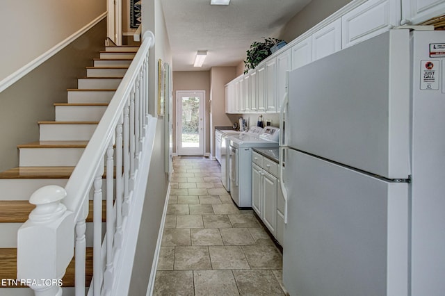 108 Waynoka Ln, Loudon, TN 37774 - kitchen with white cabinetry, baseboards, a textured ceiling, freestanding refrigerator, and washing machine and dryer